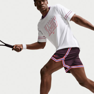 Mann im weißen T-Shirt mit Aufdruck VAMOS und weinroten Shorts spielt Tennis. Mann im weißen T-Shirt mit Aufdruck VAMOS und weinroten Shorts spielt Tennis.