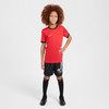 Junge in rotem T-Shirt und schwarzer Hose mit Nike-Logo.