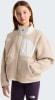 Mädchen in einem beigefarbenen Fleece-Pullover mit Stehkragen und lila Leggings.