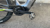 Detail eines E-Bikes: Kette, Kurbeln und Pedale auf Asphalt.