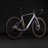 Lila Gravelbike mit buntem Rahmenaufdruck und braunen Reifen.