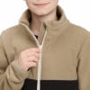 Ein Kind schließt eine beige Fleecejacke mit einem schwarzen Streifen unten.