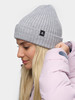 Ein Mädchen in einer grauen Strickmütze und einer rosa Jacke lächelt.