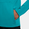 Detail eines Mannes mit der Hand in der Tasche einer türkisfarbenen Jacke.