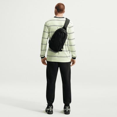 Ein Mann von hinten in gestreiftem Shirt und schwarzer Jogginghose mit Umhängetasche. Ein Mann von hinten in gestreiftem Shirt und schwarzer Jogginghose mit Umhängetasche.