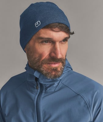 Ein Mann in einer blauen Mütze und Kapuzenjacke schaut nach rechts. Ein Mann in einer blauen Mütze und Kapuzenjacke schaut nach rechts.