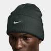 Ein Mann mit einer dunkelgrünen Nike-Mütze mit weißem Logo auf weißem Hintergrund.