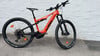 Ein orangefarbenes KTM E-Bike steht vor einer weißen Wand auf Betonboden.
