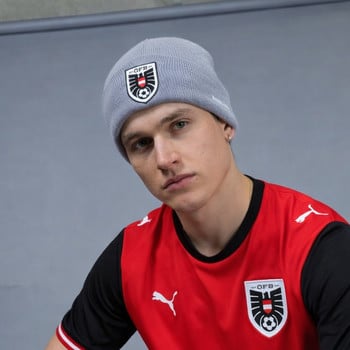 Junger Mann in grauem Hut mit Logo und rotem Fußballtrikot