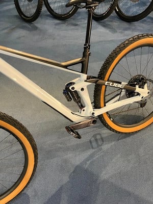 Ein weißes Mountainbike mit orangefarbenen Reifen und Cube-Logo am Rahmen. Ein weißes Mountainbike mit orangefarbenen Reifen und Cube-Logo am Rahmen.