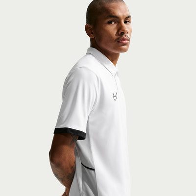 Ein Mann in einem weißen Polohemd mit schwarzem Ärmelbund und Logo. Ein Mann in einem weißen Polohemd mit schwarzem Ärmelbund und Logo.