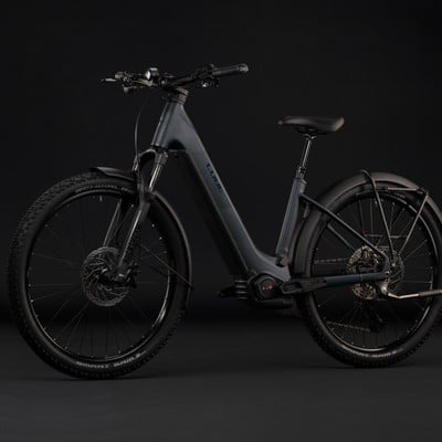 Graues Cube E-Bike mit Federung und Schutzblechen vor schwarzem Hintergrund.