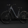 Graues Cube E-Bike mit Federung und Schutzblechen vor schwarzem Hintergrund.