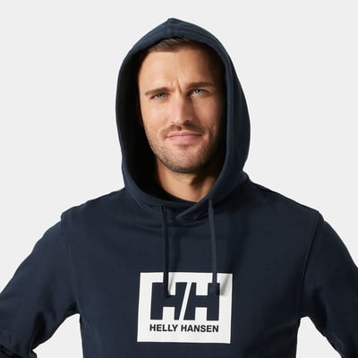 Egy férfi sötétkék kapucnis pulóverben, Helly Hansen logóval. Egy férfi sötétkék kapucnis pulóverben, Helly Hansen logóval.