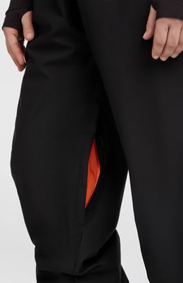 Detail einer schwarzen Hose mit oranger Tascheninnenfutter.