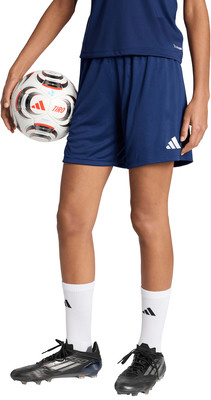Ein Mädchen hält einen Fußball in dunkelblauen Shorts und weißen Socken.