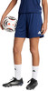 Ein Mädchen hält einen Fußball in dunkelblauen Shorts und weißen Socken.