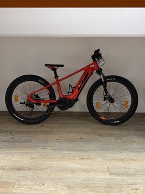 Ein rotes KTM E-Mountainbike mit dicken Reifen auf Holzboden. Ein rotes KTM E-Mountainbike mit dicken Reifen auf Holzboden.