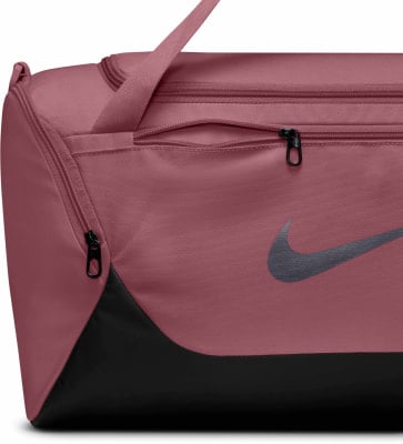 Eine rosafarbene Nike Sporttasche mit schwarzem Logo und Reißverschlüssen. Eine rosafarbene Nike Sporttasche mit schwarzem Logo und Reißverschlüssen.