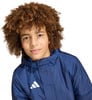 Junge mit lockigem Haar in einer dunkelblauen Jacke mit Adidas-Logo.