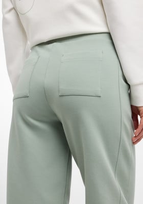 Rückseite einer hellgrünen Hose mit zwei Taschen und einem weißen Sweatshirt.