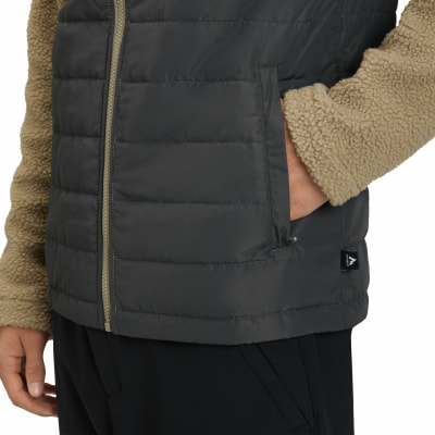 Detail einer dunkelgrauen Daunenweste mit beige Sherpa-Ärmel. Detail einer dunkelgrauen Daunenweste mit beige Sherpa-Ärmel.