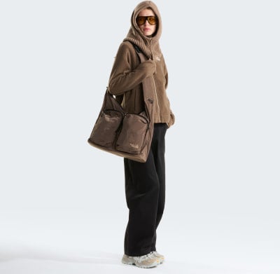 Model in brauner Kapuzenjacke und schwarzer Hose mit Umhängetasche. Model in brauner Kapuzenjacke und schwarzer Hose mit Umhängetasche.