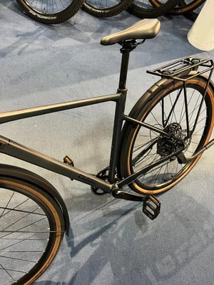 Schwarzes Fahrrad mit Gepäckträger und braunen Reifen auf blauem Teppich.