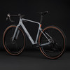Graues Gravelbike mit braunen Reifen und schwarzen Felgen vor dunklem Hintergrund.