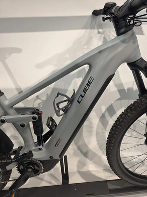Graues Cube E-Bike mit Federung und schwarzen Details auf einem Ständer. Graues Cube E-Bike mit Federung und schwarzen Details auf einem Ständer.