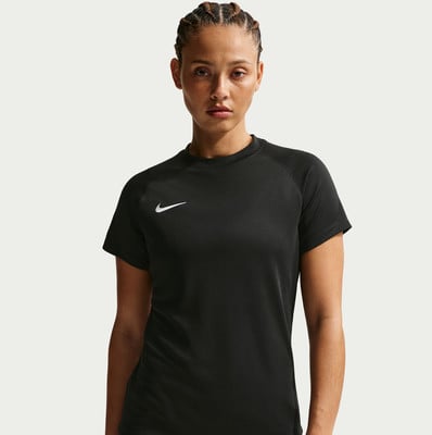 Eine Frau in einem schwarzen Nike-T-Shirt mit Logo auf der Brust posiert vor hellem Hintergrund.
