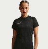 Eine Frau in einem schwarzen Nike-T-Shirt mit Logo auf der Brust posiert vor hellem Hintergrund.