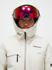 Skifahrerin in weißer Jacke und roter Brille blickt in die Kamera.