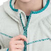 Eine Hand schließt einen Reißverschluss an einer hellgrauen Fleecejacke mit türkisfarbener Paspel.