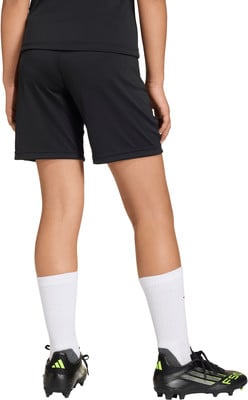 Rückansicht einer Person in schwarzer Hose, weißen Socken und Fußballschuhen.