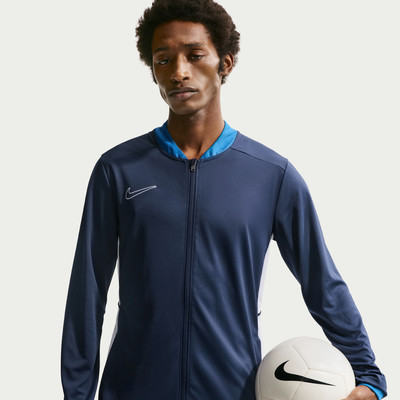 Ein Mann in einer dunkelblauen Jacke mit Ball in der Hand posiert vor Licht. Ein Mann in einer dunkelblauen Jacke mit Ball in der Hand posiert vor Licht.