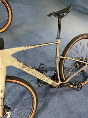Graues Cannondale-Fahrrad mit Geländereifen auf blauem Teppich. Graues Cannondale-Fahrrad mit Geländereifen auf blauem Teppich.