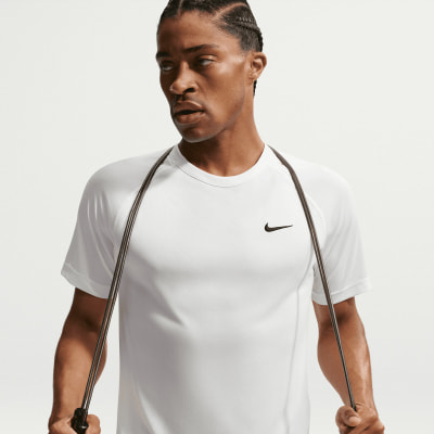 Ein Mann in einem weißen T-Shirt mit Nike-Logo hält ein Springseil. Ein Mann in einem weißen T-Shirt mit Nike-Logo hält ein Springseil.