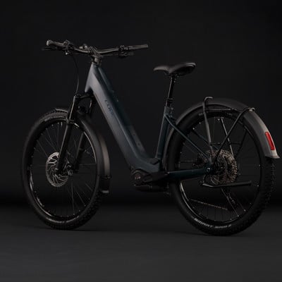 Dunkelblaues Cube E-Bike mit Schutzblechen und Gepäckträger vor schwarzem Hintergrund.