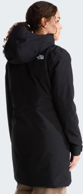 Eine Frau in einer schwarzen Kapuzenjacke mit dem Logo von The North Face auf dem Rücken. Eine Frau in einer schwarzen Kapuzenjacke mit dem Logo von The North Face auf dem Rücken.