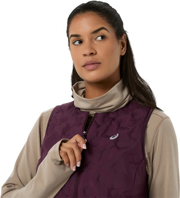 Eine Frau trägt eine weinrote Steppweste über einem beigen Rollkragenpullover. Eine Frau trägt eine weinrote Steppweste über einem beigen Rollkragenpullover.