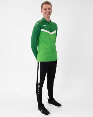 Ein Mann in einem grünen Oberteil und einer schwarzen Jogginghose steht vor weißem Hintergrund. Ein Mann in einem grünen Oberteil und einer schwarzen Jogginghose steht vor weißem Hintergrund.