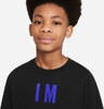 Ein Junge in einem schwarzen T-Shirt mit dem Schriftzug IM in blauen Buchstaben.