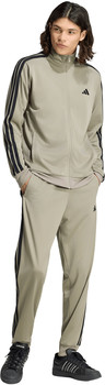 Mann in beiger Adidas-Trainingshose mit schwarzen Streifen und schwarzen Turnschuhen.