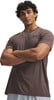 Ein Mann mit lockigem Haar trägt ein braunes T-Shirt mit Under Armour Logo.