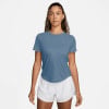 Eine Frau in einem blauen T-Shirt und weißen Shorts steht vor einem weißen Hintergrund.