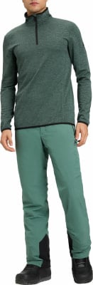 Ein Mann in einem dunkelgrünen Pullover mit Reißverschluss und grünen Hosen mit schwarzen Details. Ein Mann in einem dunkelgrünen Pullover mit Reißverschluss und grünen Hosen mit schwarzen Details.