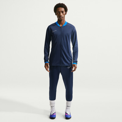 Mann in dunkelblauem Nike Trainingsanzug mit blauem Kragen und weißem Logo. Mann in dunkelblauem Nike Trainingsanzug mit blauem Kragen und weißem Logo.
