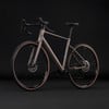 Elegantes graues Gravelbike mit braunen Reifen vor schwarzem Hintergrund.