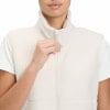 Eine Frau schließt eine cremefarbene Sherpa-Weste über einem weißen T-Shirt.